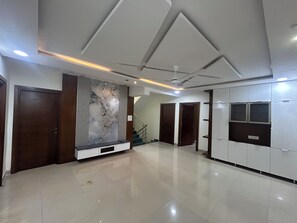 A spacious room with a marble wall, a ceiling fan, and a large wardrobe.