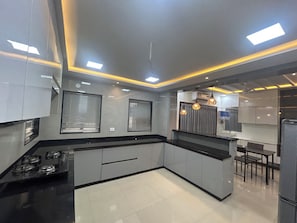 A modern kitchen with a central island, recessed lighting, and a dining area with a bar.