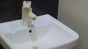 Un lavabo de salle de bain blanc, doté d’un seul robinet et d’un drain.