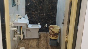 Une salle de bain équipée de toilettes, d’un lavabo et d’une poubelle.