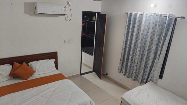 Une chambre d’hôtel avec un lit, une armoire, un miroir et un rideau.