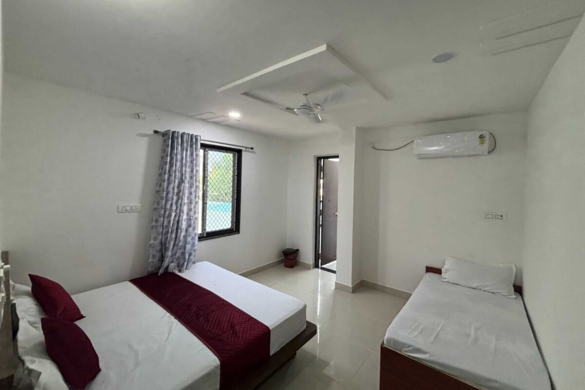 Habitación de hotel con dos camas, una ventana con cortinas, un aire acondicionado y un ventilador de techo.