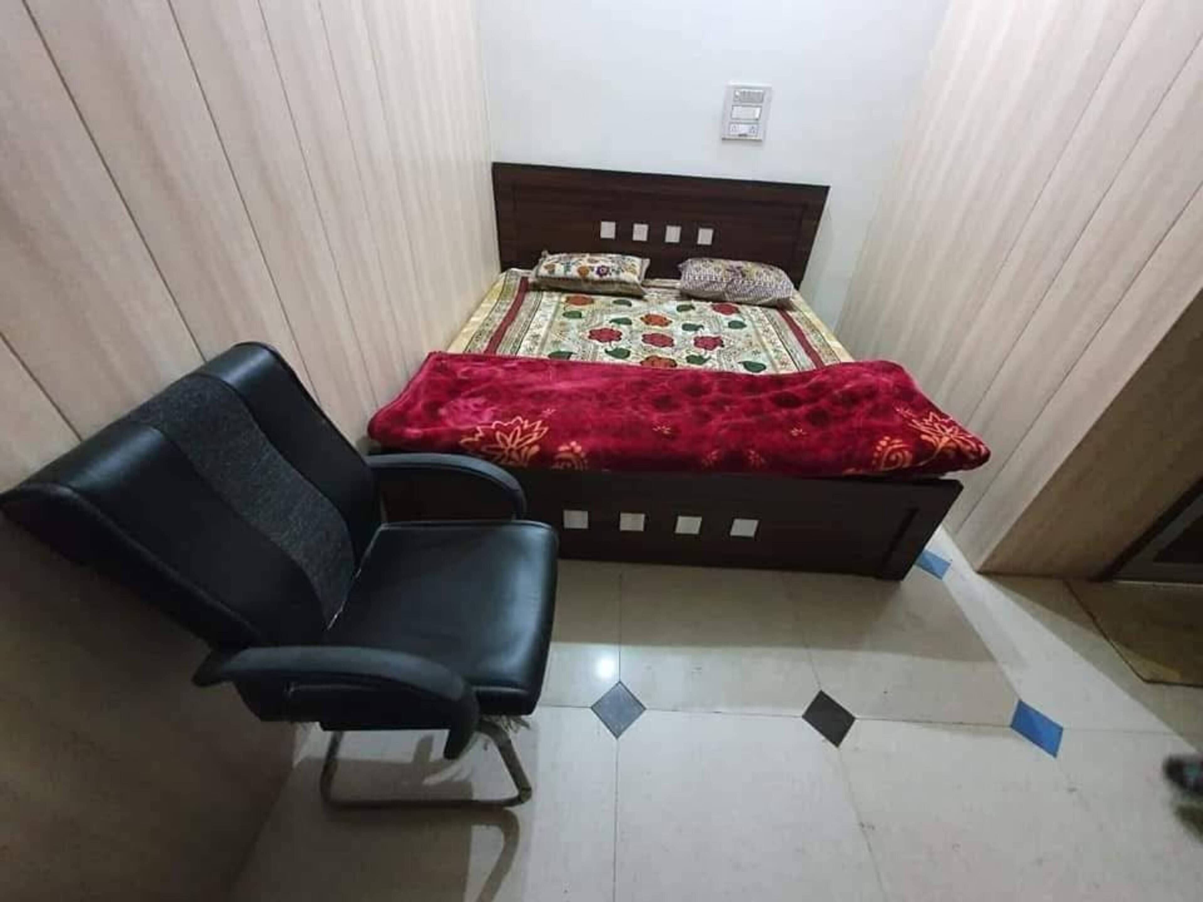 A bedroom with a bed, a chair, and a tiled floor.