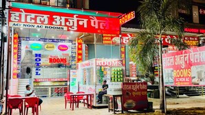 A hotel with multiple room types advertised, including AC and non-AC options, and a sign for Happy Complex. - Hotel Arjun Palace (Shri Madhopur)