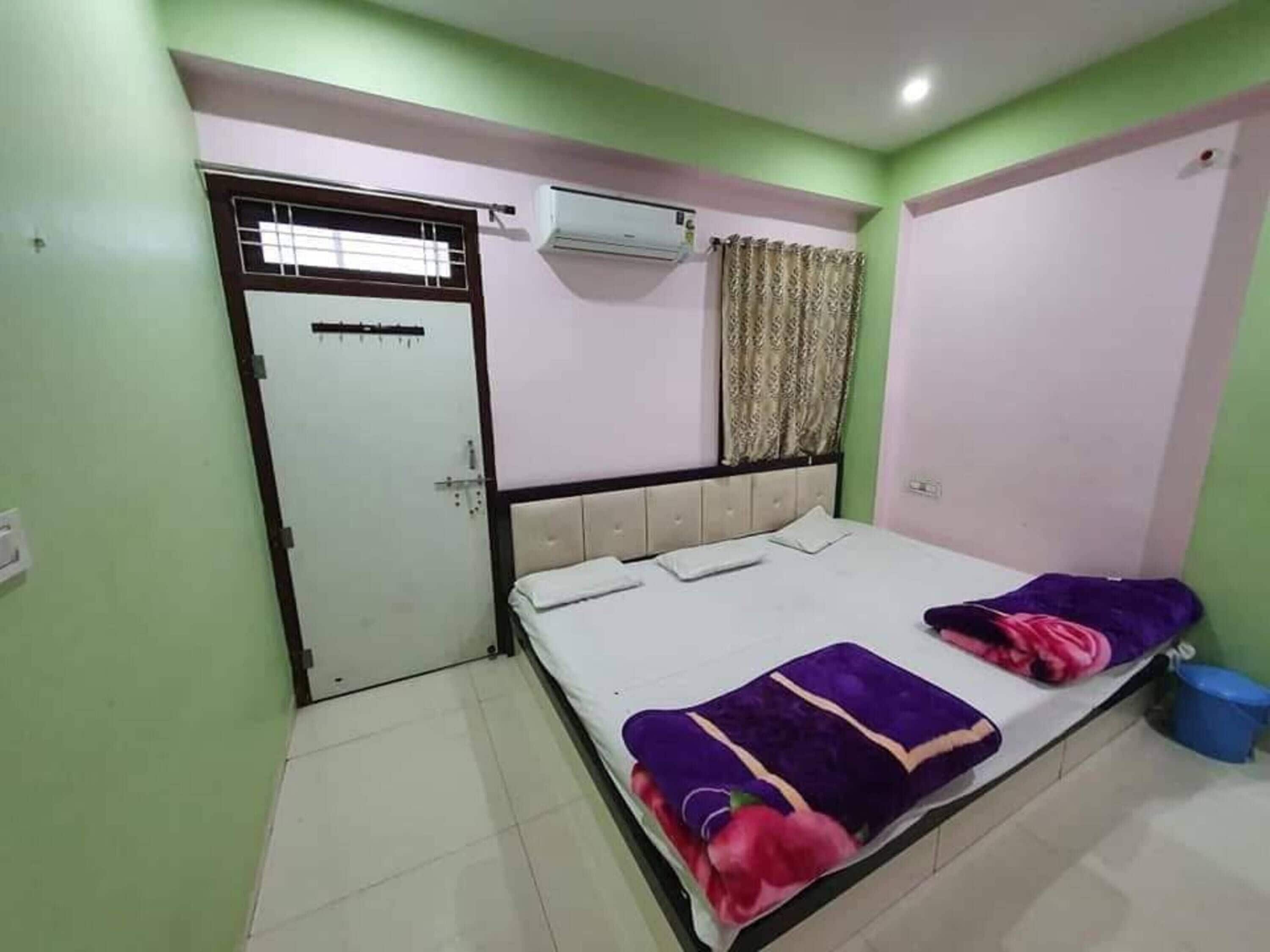 Un dormitorio con cama, aire acondicionado, una puerta y una cortina.