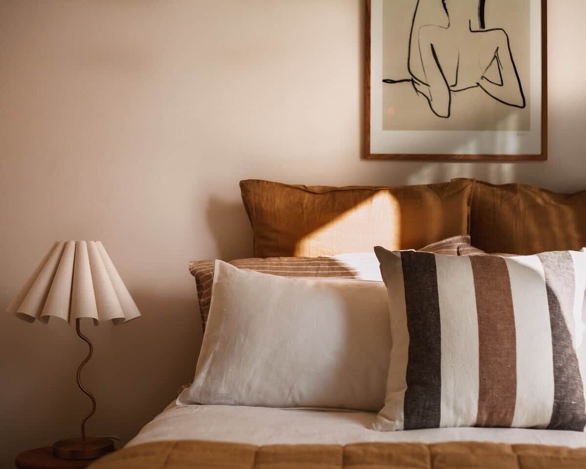 A bed with multiple pillows and a lamp beside it.