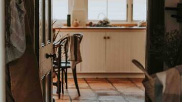 Una cocina con piso de madera, lámpara colgante y armarios.