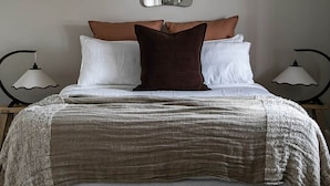 Quarto com uma cama grande, duas luminárias de apoio, um lustre e um espelho na parede.