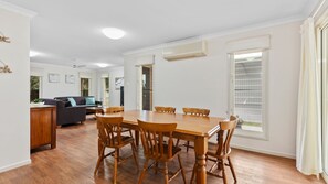 Un coin repas avec une table et des chaises en bois, un canapé et, au fond, une cuisine.