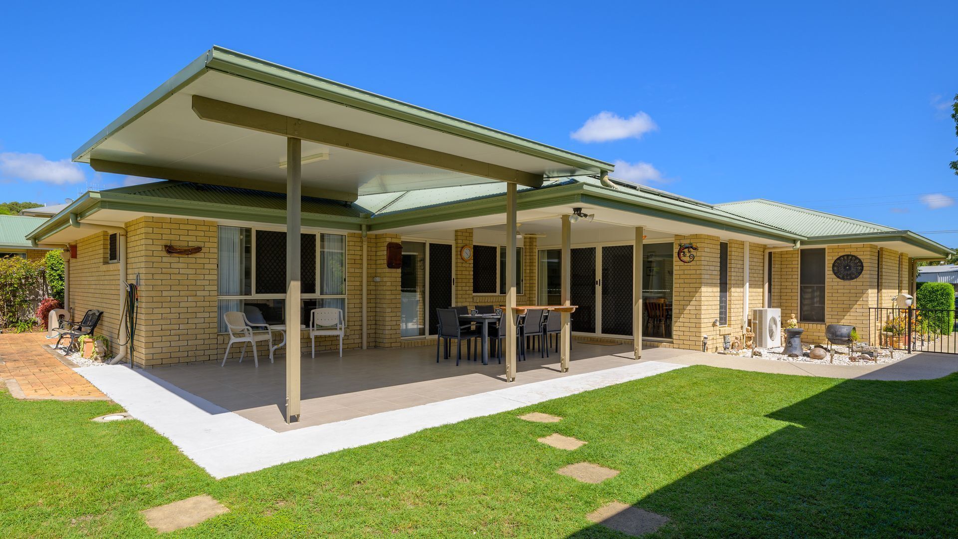 Un patio couvert, aménagé avec du mobilier d’extérieur, et une maison en briques.