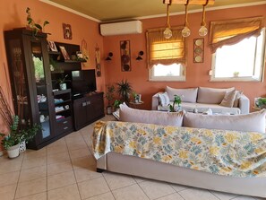 Una sala de estar con sofá, televisión y plantas decorativas.
