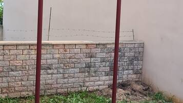 A metal bar structure in a grassy area with a stone wall and a building in the background.