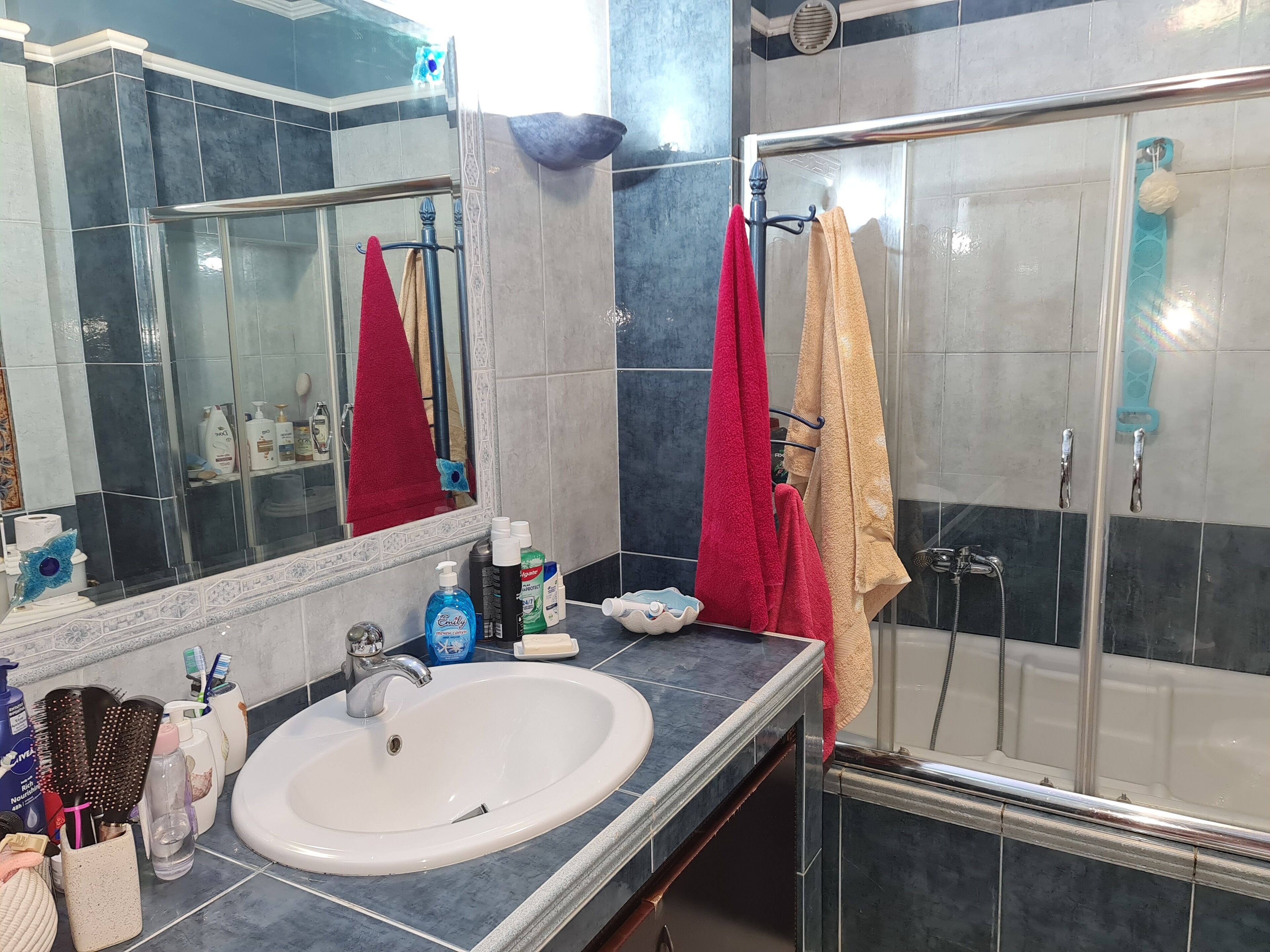 A bathroom with a white sink, a mirror, and a glass shower enclosure.