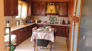A kitchen with wooden cabinets, a dining table with chairs, and a window with curtains.