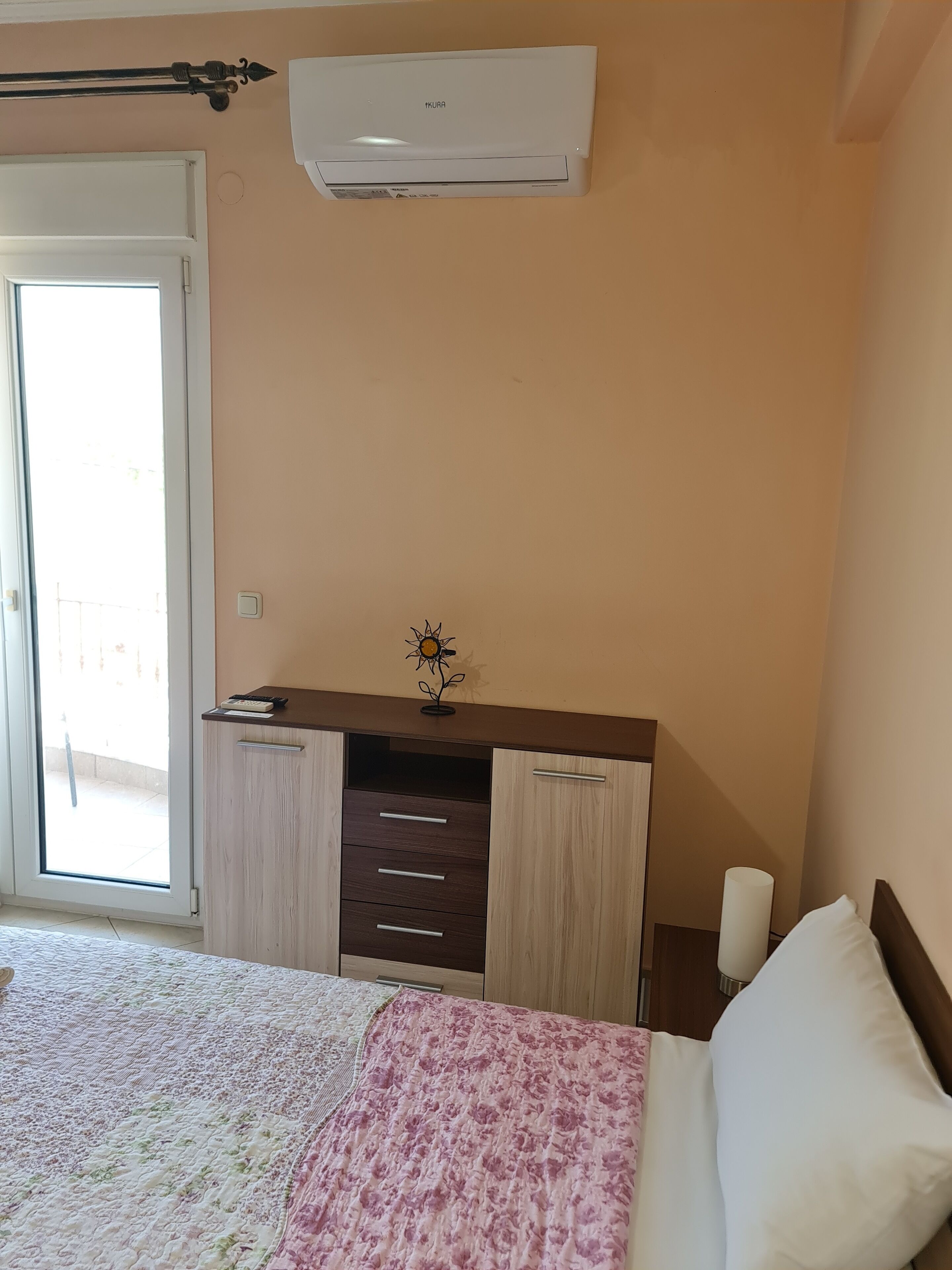 Un dormitorio con cama, mesita de noche, armario y equipo de aire acondicionado.