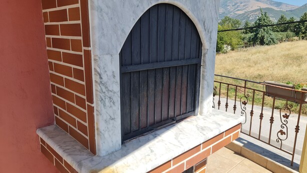 A balcony with a marble ledge, a metal railing, and a view of a mountainous landscape.