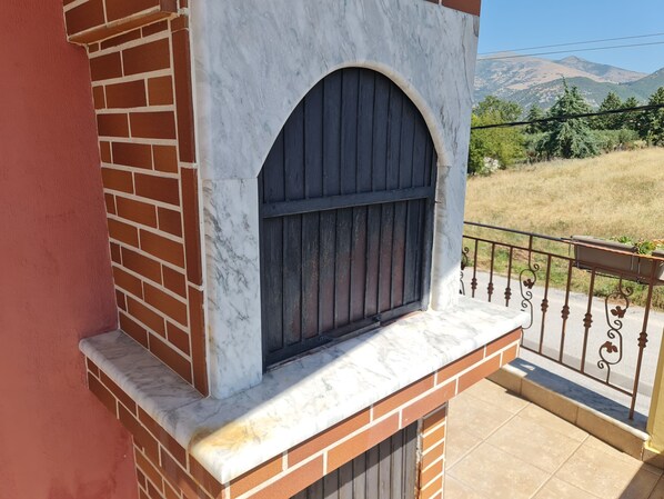 A balcony with a marble ledge, a metal railing, and a view of a mountainous landscape.