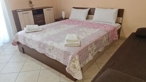 A neatly made bed with a floral bedspread and two pillows, a bedside table with a lamp, and a wooden wardrobe.