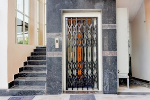 A building entrance with a metal gate, a set of stairs, and a wall-mounted elevator control panel. - Super Collection O Vizag Water World (Visakhapatnam)