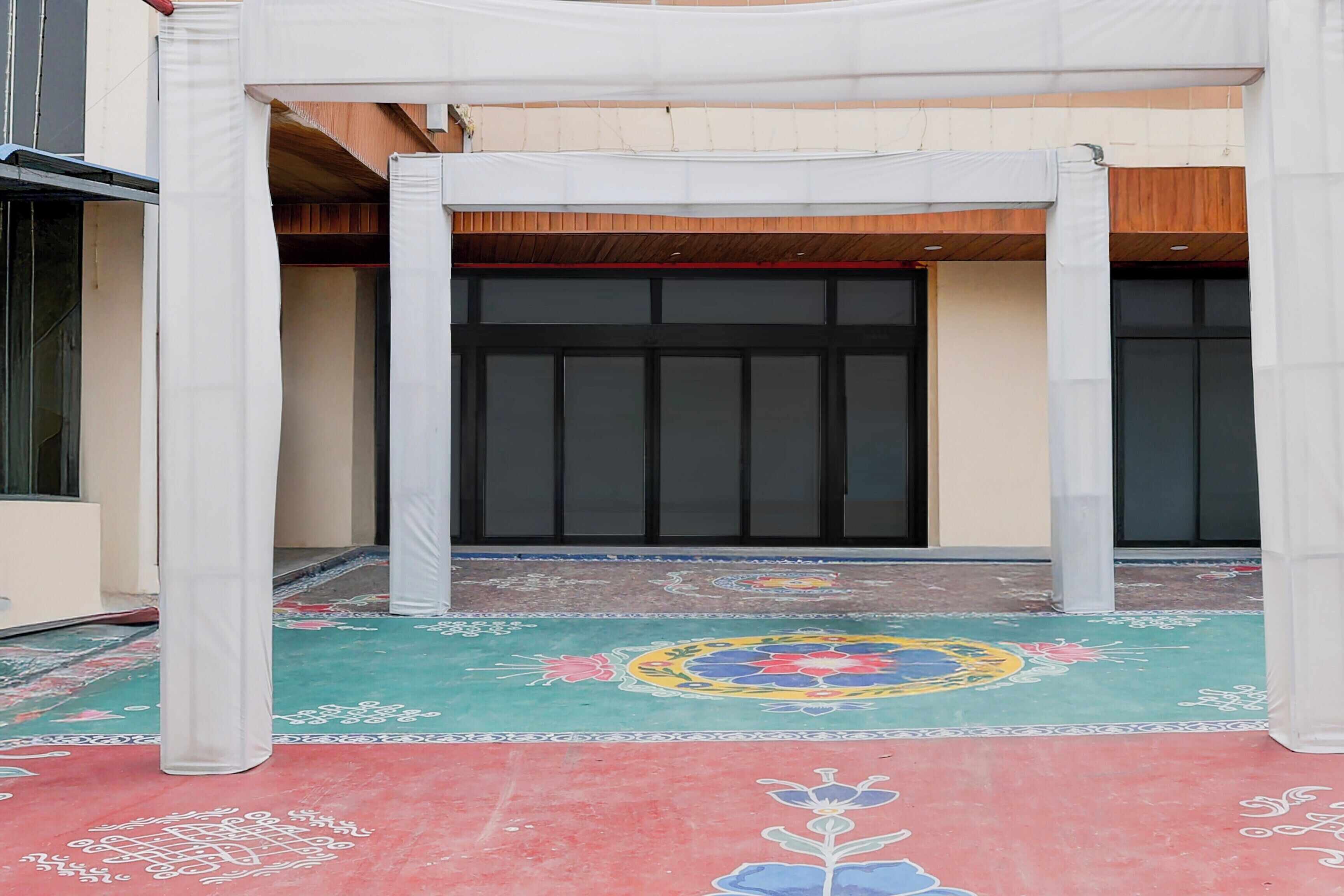 Uma área externa coberta com piso estampado, uma porta grande e uma estrutura branca.