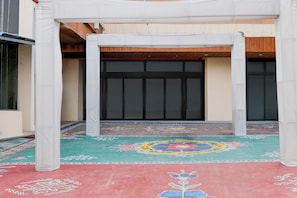 Un espacio al aire libre techado con suelo estampado, una puerta grande y una estructura blanca.