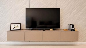 Ein Flachbildfernseher auf einer schlichten Holzkommode vor einer strukturierten Wand.