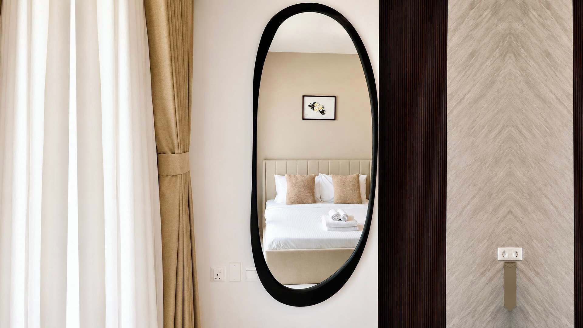 Une chambre à coucher avec un lit, un miroir et un tableau accroché au mur.