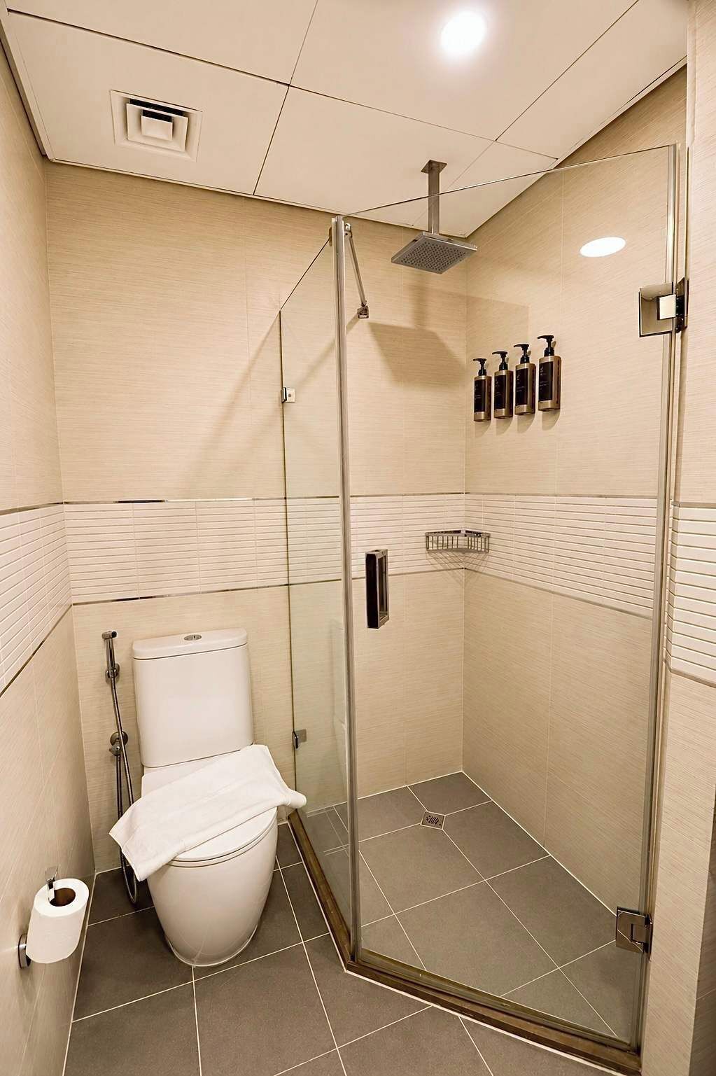 Un baño moderno con cabina de ducha de vidrio, inodoro y perchero para toallas.