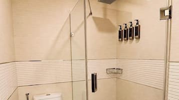 Un baño moderno con cabina de ducha de vidrio, inodoro y perchero para toallas.