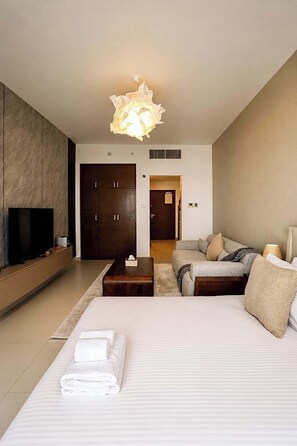 Een moderne hotelkamer met een groot bed, een bank, een televisie en een bijzondere lamp.
