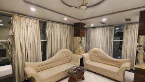 Una sala de estar con dos sofás beige, una mesa de centro de vidrio y un ventilador de techo.