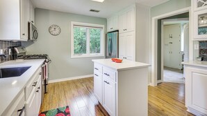 A kitchen with white cabinets, a stainless steel refrigerator, a gas stove, and a window with a view of trees. - Updated Home Minutes to Downtown and Beach! (Sister Bay)