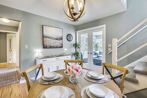 A dining area with a wooden table set for four, a chandelier, and a painting on the wall. - Updated Home Minutes to Downtown and Beach! (Sister Bay)