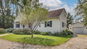 A two-story house with a front porch, a garage, and a well-maintained lawn. - Updated Home Minutes to Downtown and Beach! (Sister Bay)