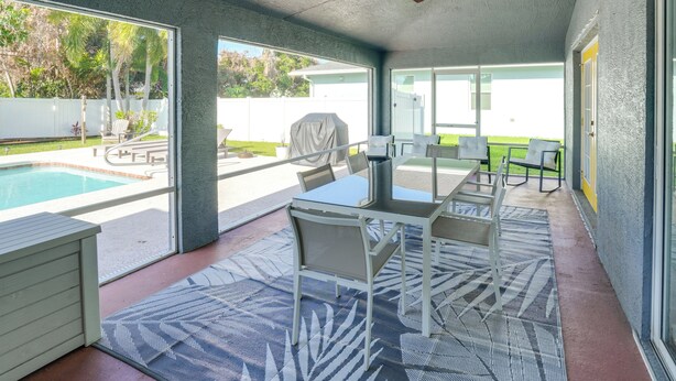 Un'area esterna coperta con piscina, tavolo e sedie, e una ventola a soffitto.