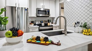 Una cocina moderna con armarios blancos, electrodomésticos de acero inoxidable y encimera de mármol.