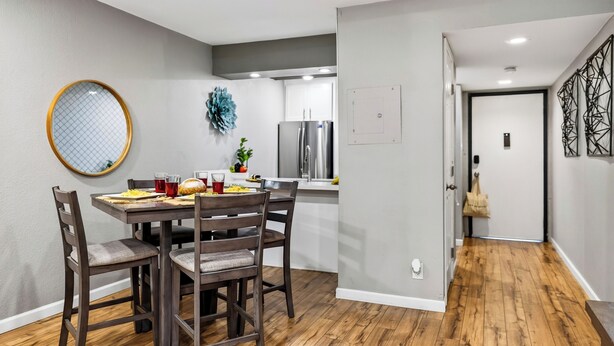 Un comedor con una mesa y sillas de madera, un espejo redondo y un adorno en la pared.