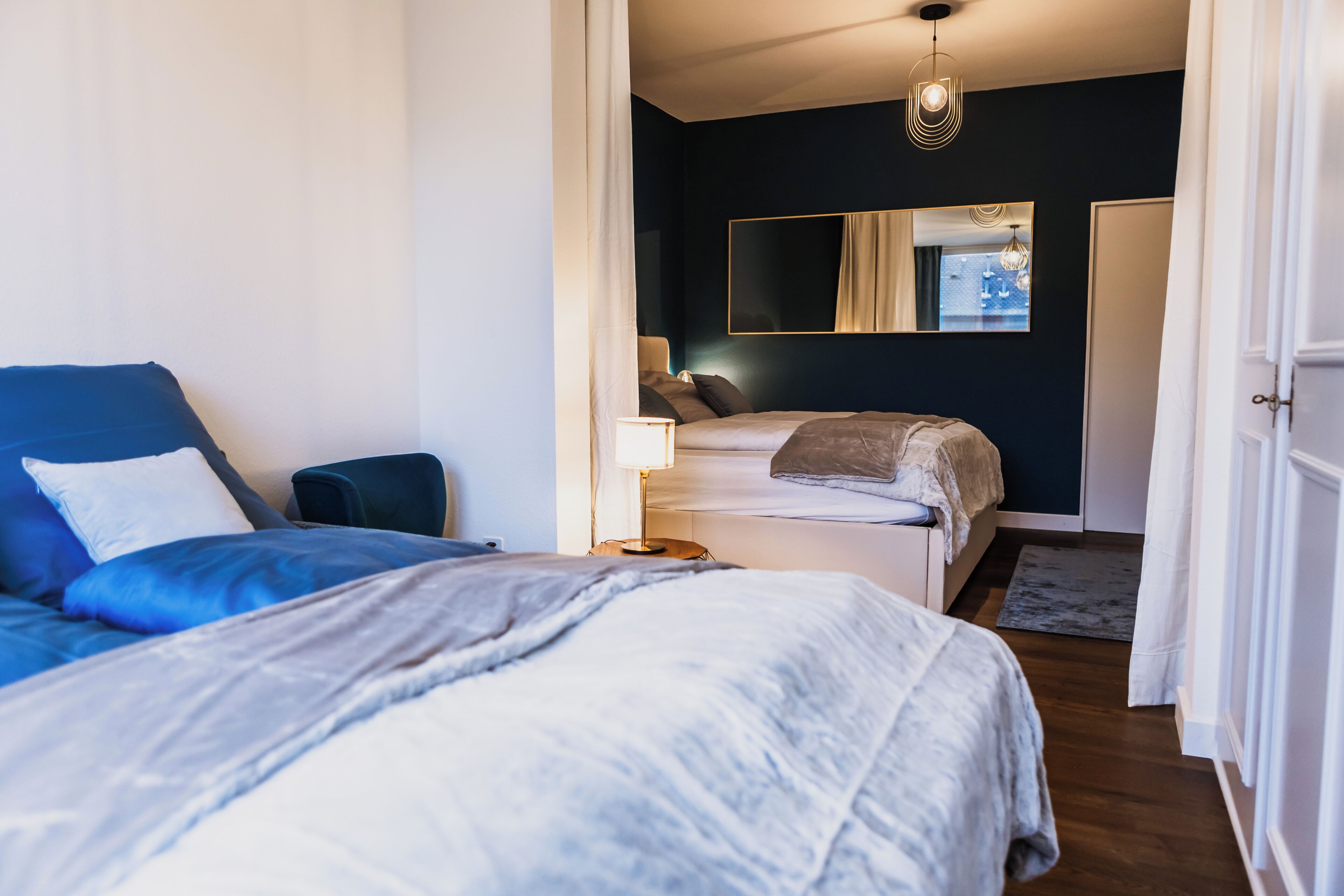 Ein Schlafzimmer mit zwei Betten, einem Spiegel und Blick ins Freie.