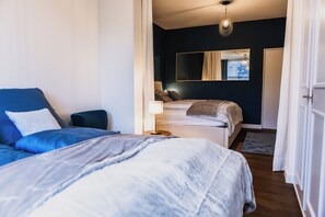 A bedroom with two beds, a mirror, and a view of the outside. - Stylish penthouse in the old town with generous rooftop terrace facing city hall (Basel)