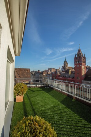 Ein Balkon mit Blick auf eine Stadtansicht, darunter ein markanter Turm und traditionelle Gebäude.