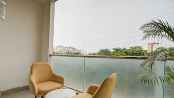 Un balcón con dos sillas y una pequeña mesa, con vistas a un paisaje urbano con edificios y zonas verdes.