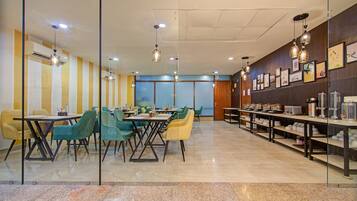 Een moderne eetruimte met tafels, stoelen, een buffet en kunstwerken aan de muur.