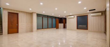 A spacious, well-lit hallway with a tiled floor, wooden doors, and a large window.