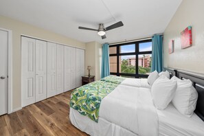 A bedroom with a bed, a ceiling fan, a window with curtains, and a door. - Charming 2BD w Ocean Views Near Beach - KV F401 (Lahaina)