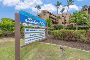 Un letrero de Kahana Villa que muestra claramente la arquitectura del edificio y la vegetación circundante.