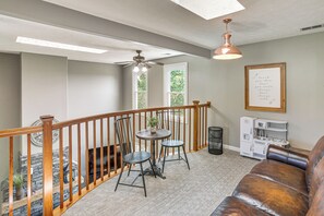 A cozy living area with a wooden staircase, a dining table with chairs, a fireplace, and a kitchen area with a vintage stove. - Day Trip to Nashville! Large Home on 5 Acres (Springfield)