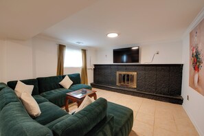 Ein Wohnzimmer mit einem grünen Sofa, einem Kamin und einem an der Wand befestigten Flachbildfernseher.