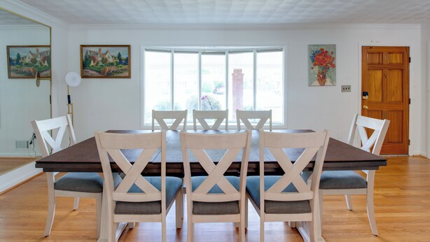 Une salle à manger avec une grande table, six chaises et une porte en bois.