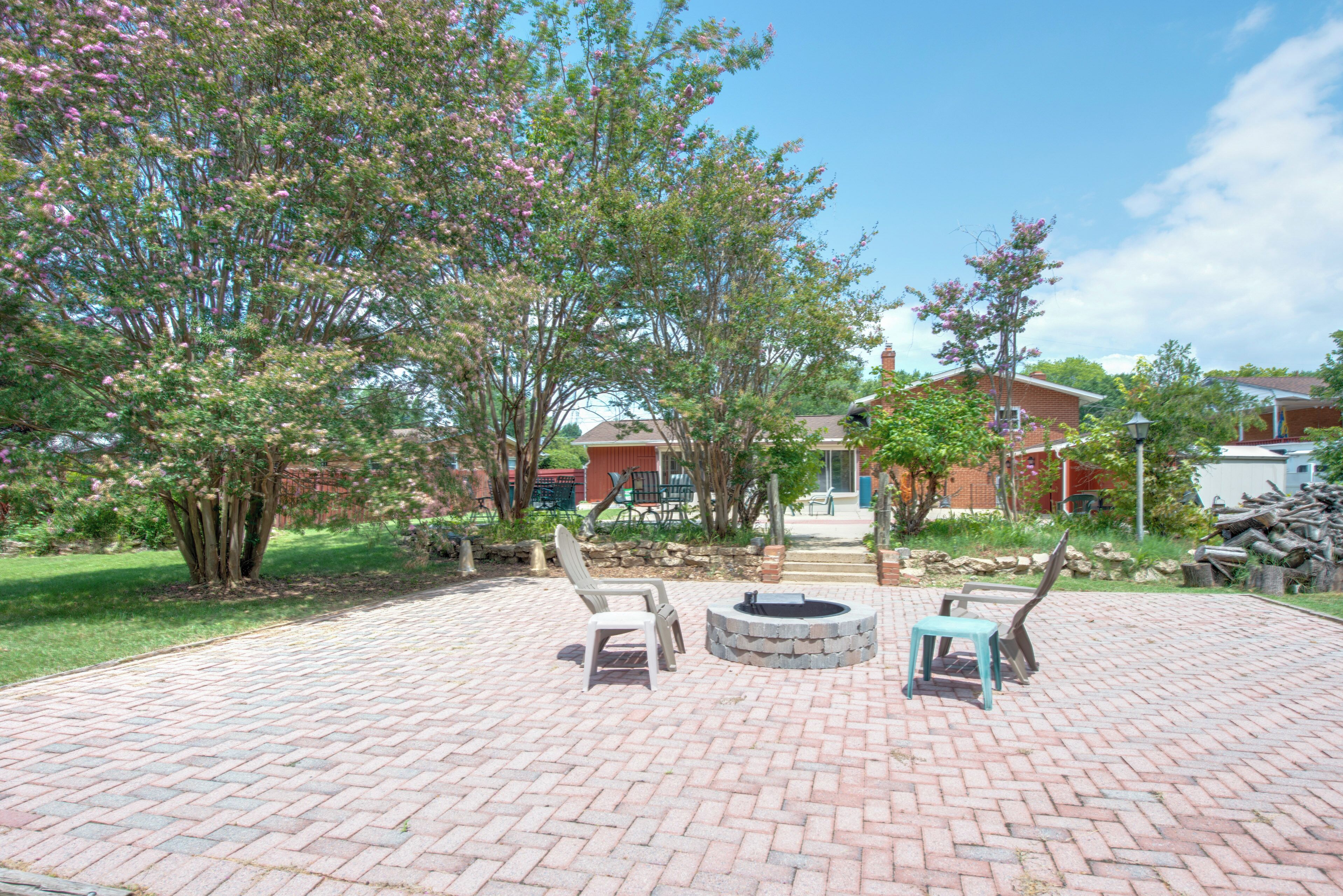 A patio area with a fire pit, outdoor seating, and a brick pathway.