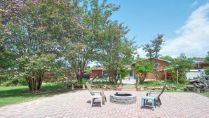 Un espace patio avec un foyer, des sièges d’extérieur et un chemin en briques.